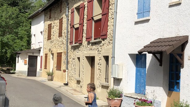 Ruas com edifícios de fachadas em pedra e persianas de madeira.