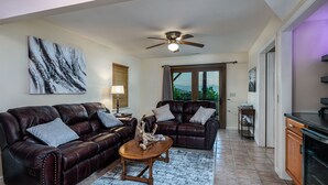 A living room with a dark brown leather sofa, a wooden coffee table, and a ceiling fan. - High View Heights stunning views and complete privacy (Bryson City)