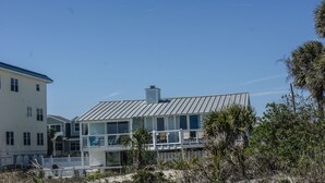 A modern two-story house with a metal roof, large windows, and a balcony. - Oceanfront Tybee Cottage | Private Hot tub & Beach Access (Tybee Island)