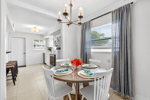 A dining area with a round table, white chairs, and a chandelier.