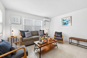 A modern living room with a sofa, armchair, coffee table, and a bench.