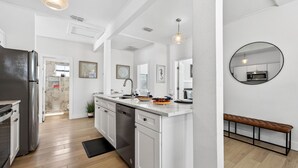 A modern kitchen with white cabinetry, a stainless steel refrigerator, and a wooden floor.