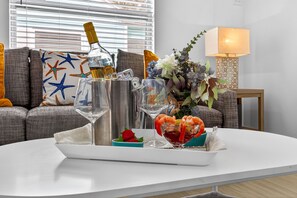 A dining table with a tray of food, a bottle of champagne, and a vase of flowers.