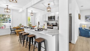 A modern kitchen with white cabinetry, a central island with stools, and pendant lighting.