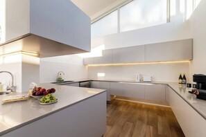 Eine moderne Küche mit einer zentralen Kochinsel, eingebauten Geräten und Holzboden.