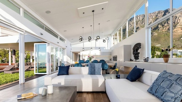 A modern interior with a large L-shaped sofa, a dining area, and a kitchen.