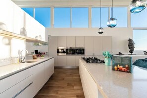 A modern kitchen with a central island, stainless steel appliances, and pendant lighting.