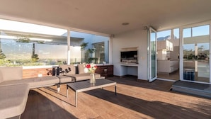 A modern living space with a sofa, coffee table, and a kitchen area with a grill.
