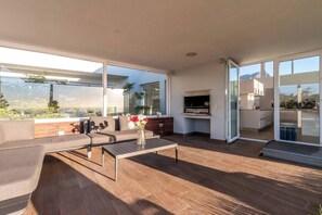A modern living space with a sofa, coffee table, and a kitchen area with a grill.