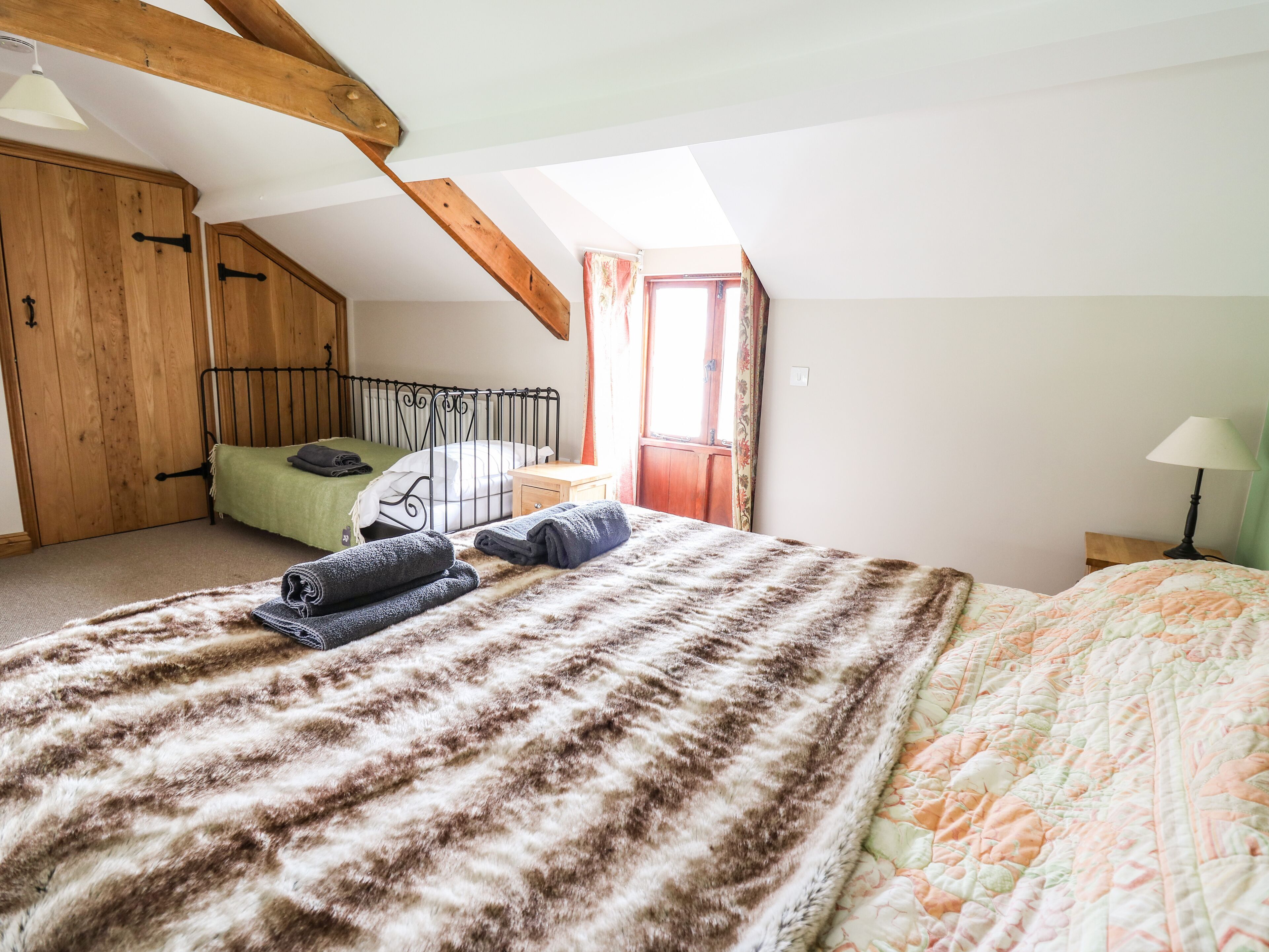 Un dormitorio acogedor con una cama grande, un armario de madera, una mesita de noche pequeña y una ventana con cortinas.