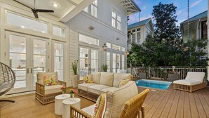 A spacious outdoor deck with a pool, wicker furniture, and a view of neighboring buildings. - President`s Row in WaterColor with Heated Pool, LSV, Bikes! STEPS to BEACH CLUB! RENOVATED 2025! (Santa Rosa Beach)