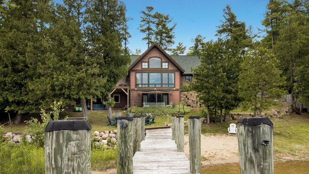 Un sentier en bois mène à une maison dotée d’une grande fenêtre et d’une fondation en pierre.