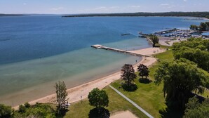 Une zone côtière dotée d’une jetée qui s’avance dans l’eau, d’une plage de sable et d’un port de plaisance où sont amarrés des bateaux.