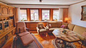 Una sala de estar acogedora con un sofá, sillones, una mesa de centro y un aparador de madera.