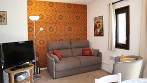 A living room with a sofa, a television, a lamp, and a poster on the wall. - Ski-in/ski-out & foot of the slopes, 5th floor, balcony, tv, 33m², Les Orres (Les Orres)