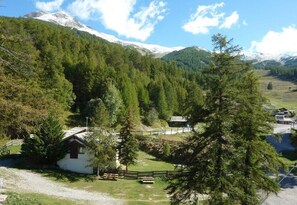 Une cabane entourée d’une forêt dense et de montagnes.
