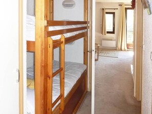 A bunk bed room with a small window and a door leading to another room.