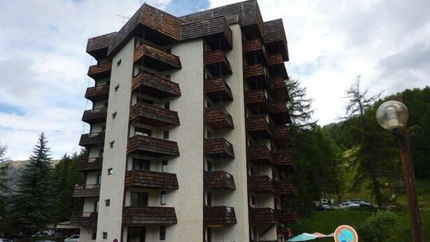 A multi-story building with balconies, parked cars, and a no parking sign. - Ski-in/ski-out & foot of the slopes, 5th floor, balcony, tv, 33m², Les Orres (Les Orres)