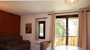 A living room with a sofa, a small table, a radiator, and a window with curtains. - Ski-in/ski-out & foot of the slopes, 5th floor, balcony, tv, 33m², Les Orres (Les Orres)