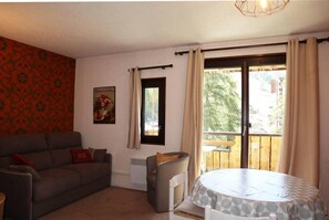 A living room with a sofa, a small table, a radiator, and a window with curtains.