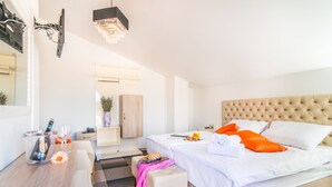 Una habitación de hotel moderna con cama, mesita de noche y un pequeño rincón de descanso.