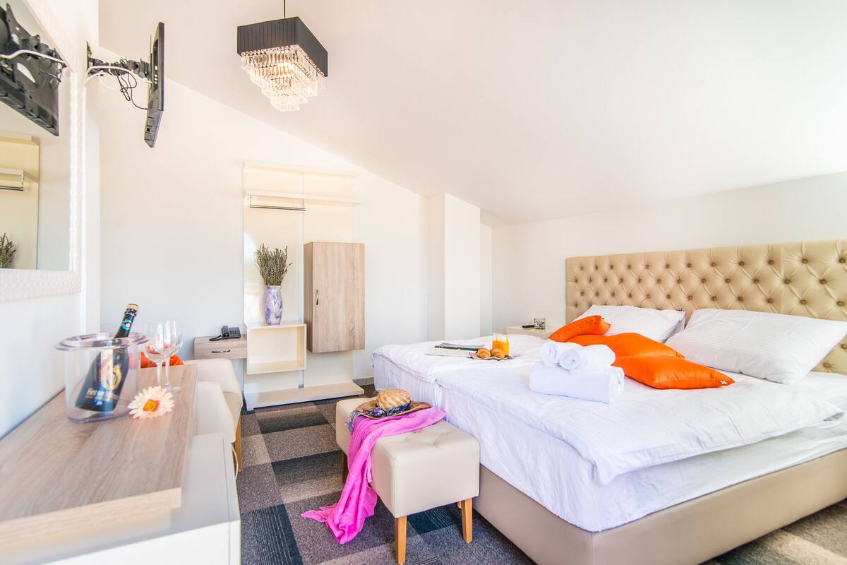 A modern hotel room with a bed, bedside table, and a small seating area.