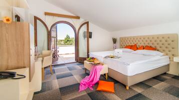 Ein Hotelzimmer mit Bett, Schreibtisch, Stuhl, einem kleinen Tisch mit Obstkorb und Blick ins Freie.