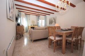 Un coin repas avec une table et des chaises en bois, un canapé et un lustre.