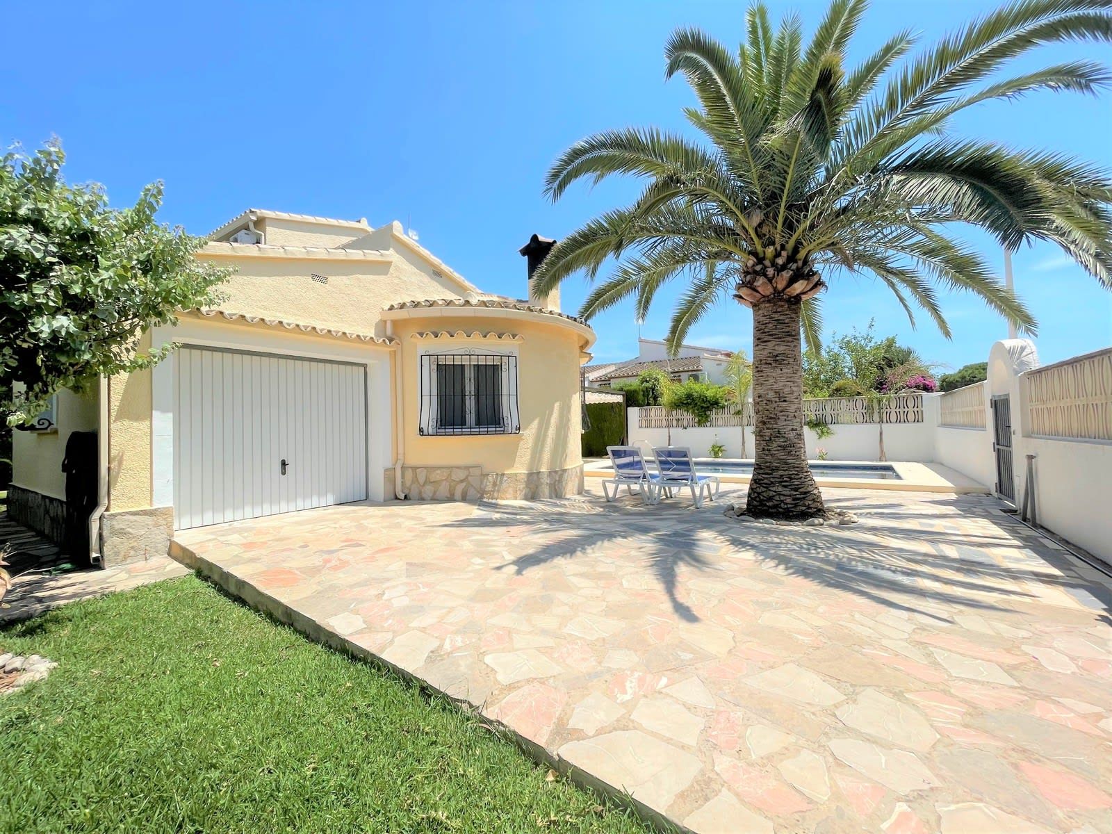 Una casa amb un patio de pedra, una palmera i una piscina.