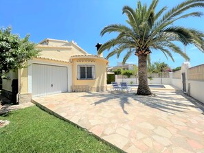 Une maison avec une terrasse en pierre, un palmier et une piscine.