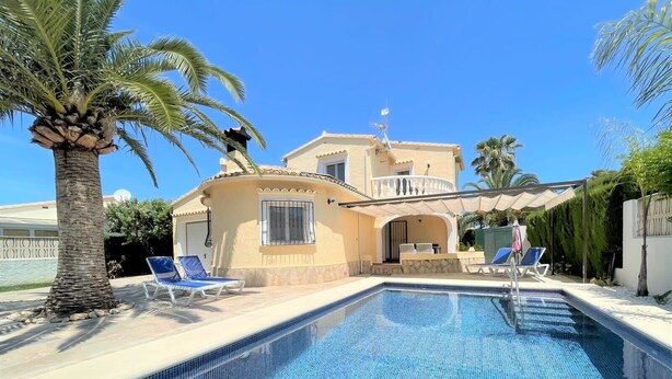 Una casa de dos pisos con piscina, palmeras y un patio cubierto.