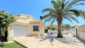 Una casa con un patio de piedra, una palmera y un portón de garaje blanco.