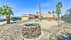 Un patio con un hogar de piedra, palmeras y un edificio de techo rojo.