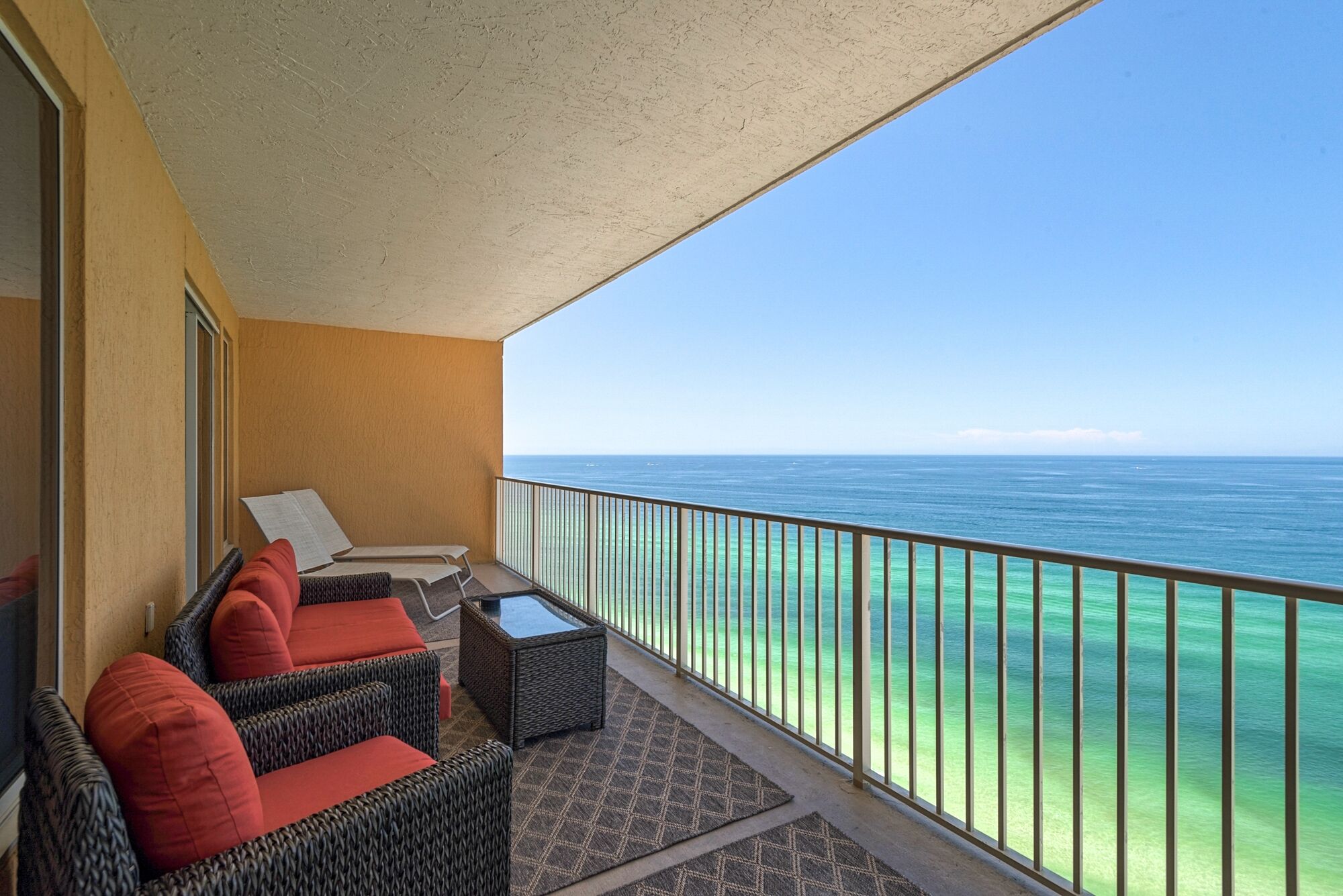 A balcony with wicker furniture and a view of the ocean.