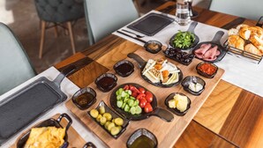 A dining table with various foods and a wine rack in a rustic interior. - Solo Cave Suites (Ürgüp)