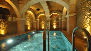 An indoor swimming pool with stone arches and warm lighting. - Solo Cave Suites (Ürgüp)
