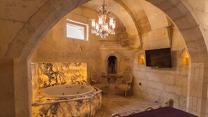 A luxurious bathroom with a marble sink, a large bathtub, and two chairs. - Solo Cave Suites (Ürgüp)