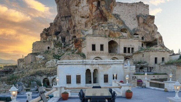 A rooftop terrace with a large rock formation in the background, furnished with outdoor seating and tables. - Solo Cave Suites (Ürgüp)