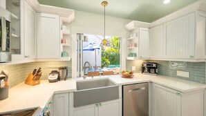 A modern kitchen with white cabinetry, a central island, and a view of a pool. - **SOUTHERNMOST BLISS @ OLD TOWN** Home & Pool + Last Key White Glove Service... (Key West)