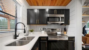A modern kitchen with black cabinets, stainless steel appliances, and a white countertop.