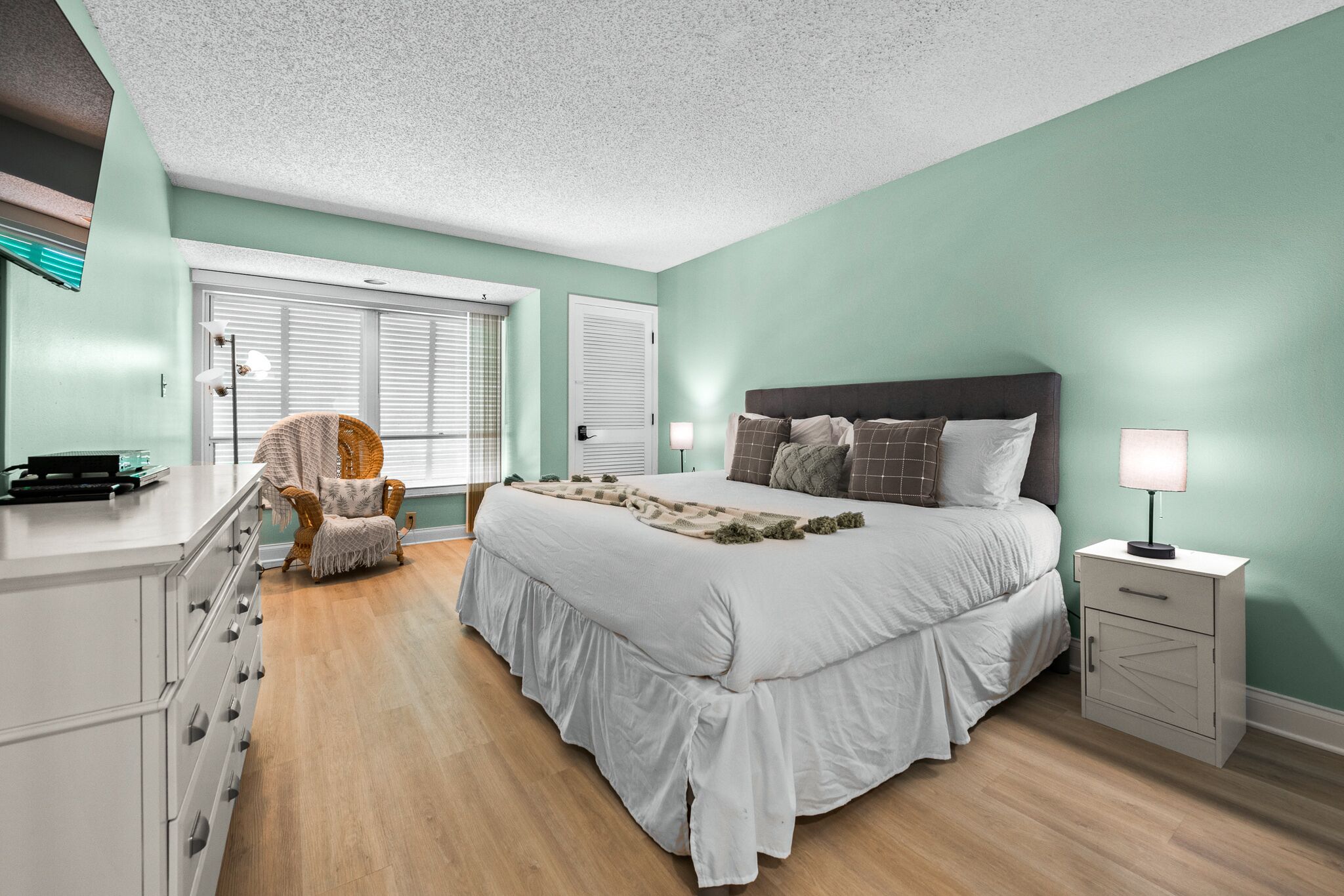 A bedroom with a bed, bedside tables, a chair, and a dresser.
