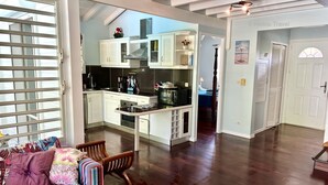 Un salón espacioso con suelo de madera, una mesa de comedor con sillas y una cocina con armarios blancos y una estufa.