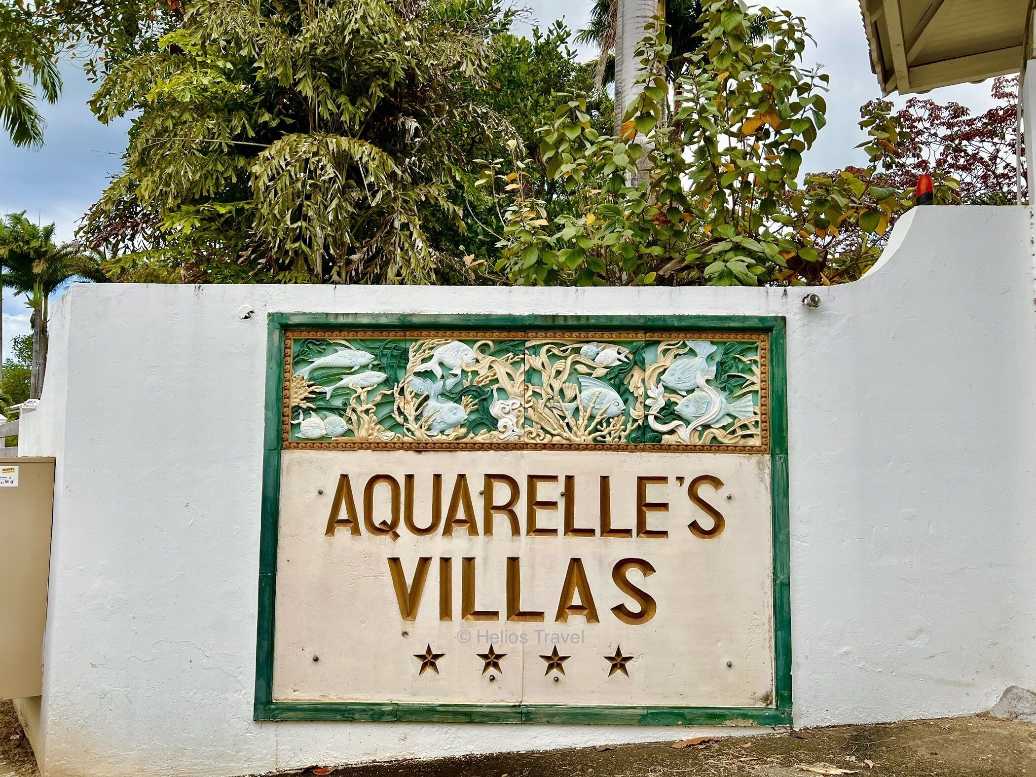 Schild für 'Aquarelle's Villas' mit dekorativem Rahmen, der Fische und Meerespflanzen zeigt.
