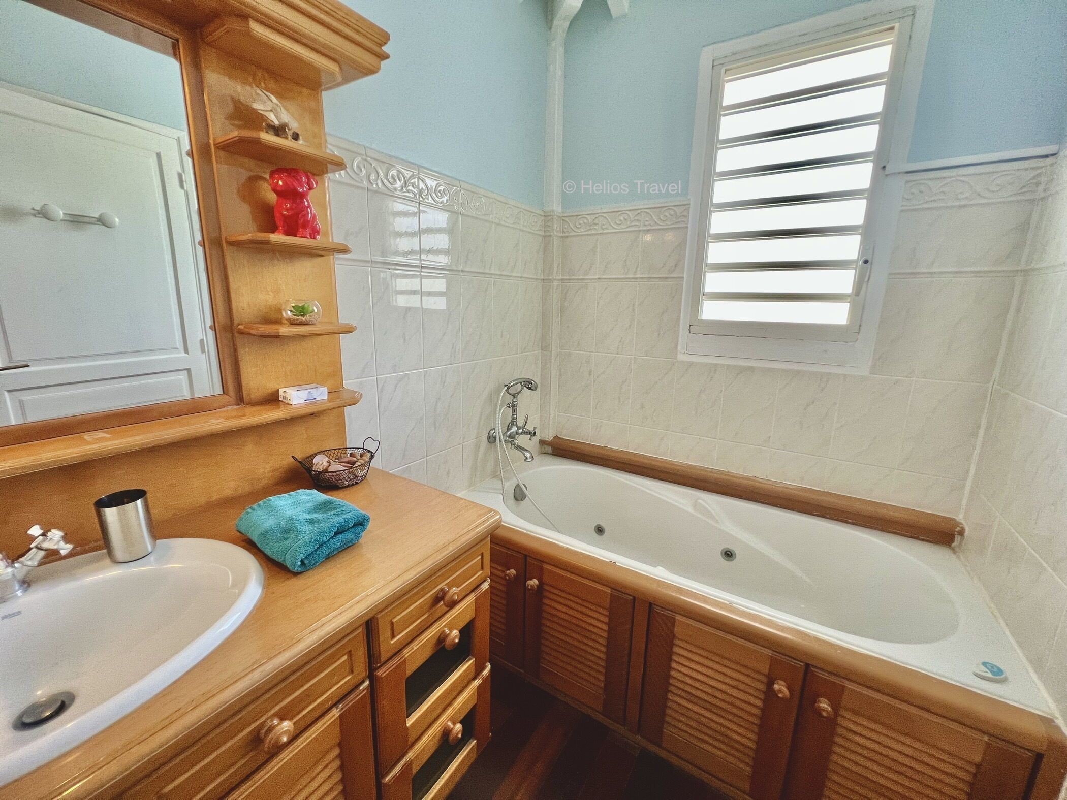 Une salle de bain avec une baignoire, un lavabo, des meubles en bois et un miroir.