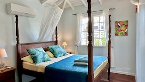 Una cama con dosel, una mesita de noche con lámpara y una ventana con cortinas.