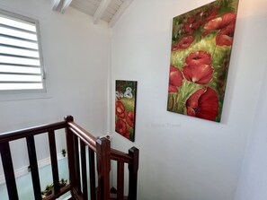 Een trap met houten leuningen en twee bloemschilderijen aan de wand.