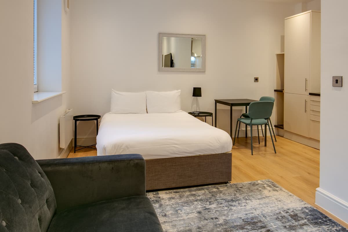 A modern hotel room with a bed, a small desk, a chair, and a television.