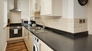 A modern kitchen with a black countertop, stainless steel appliances, and white cabinetry. - Charles Hope Apartments Swindon (Swindon)