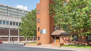 A modern building with a cylindrical brick tower, large windows, and a tree-lined street. - Charles Hope Apartments Swindon (Swindon)