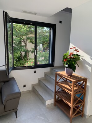 Ein modernes Interieur mit einem großen Fenster, einer Treppe, einem Holztisch und einem grauen Sofa.